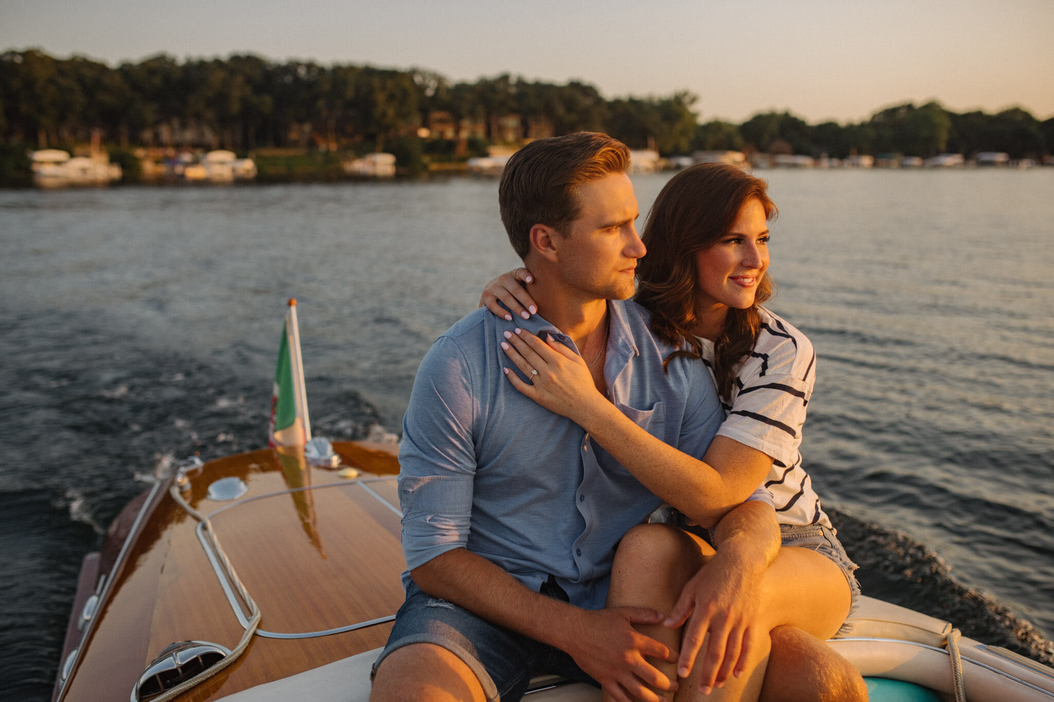 Engagement photos of a couple on a wooden boat in Okoboji, Iowa