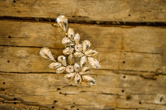 A cluster of clear, teardrop-shaped gemstones arranged in a floral design rests on a weathered wooden surface. by Justin Salem Meyer