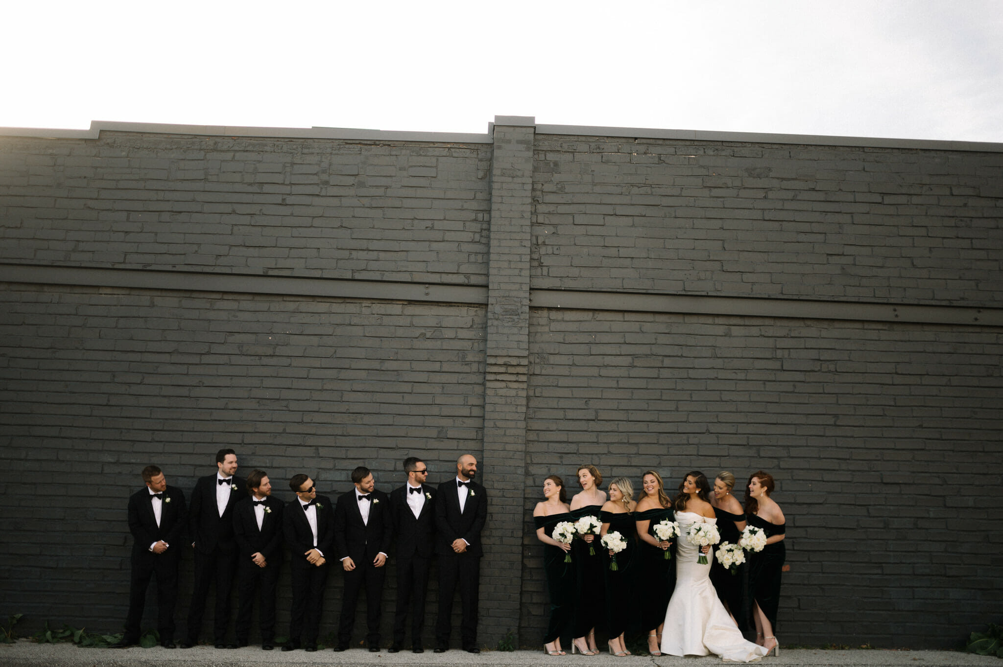 Wedding Party standing on a black wall
