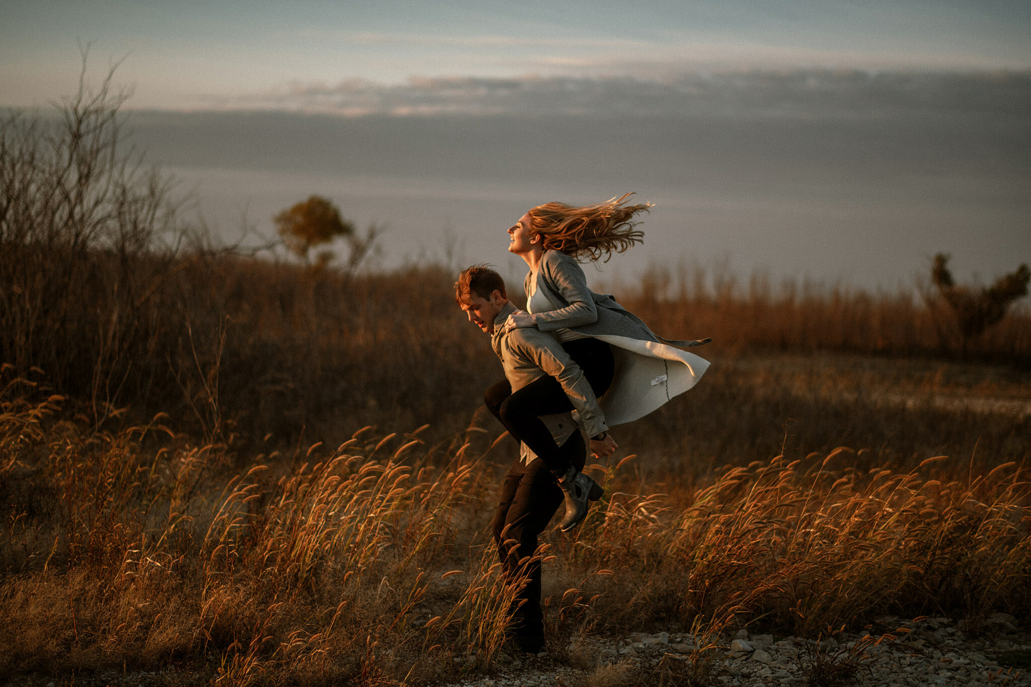 Man giving woman a piggy back ride facing the setting sun