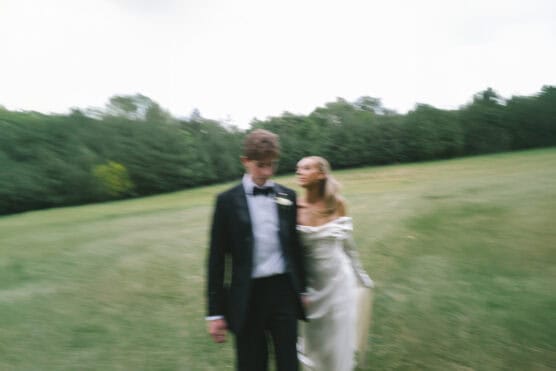 blurry beautiful couple walking in a lush green field by justinsalemmeyer
